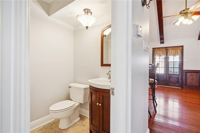 bathroom with hardwood / wood-style floors, beamed ceiling, vanity, ceiling fan, and toilet