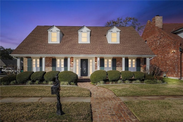 cape cod-style house featuring a yard and a porch