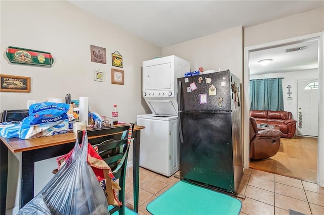 laundry area featuring light tile patterned flooring and stacked washer and dryer