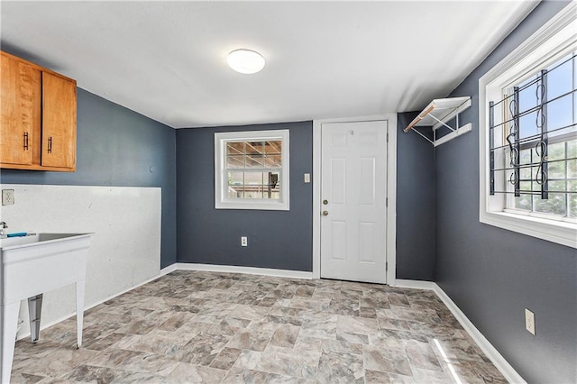 clothes washing area with cabinets and a wealth of natural light