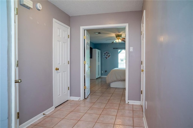 corridor featuring light tile patterned floors and a textured ceiling