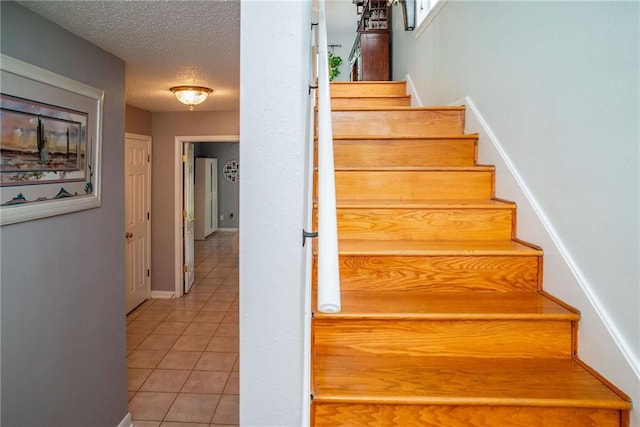 staircase featuring tile patterned floors and a textured ceiling