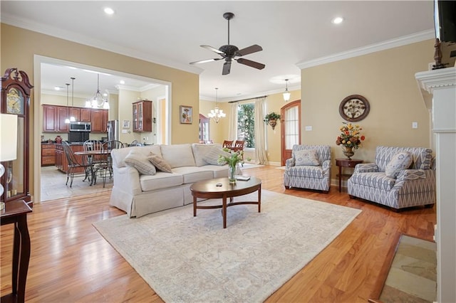 living room with ceiling fan with notable chandelier, light hardwood / wood-style flooring, and ornamental molding