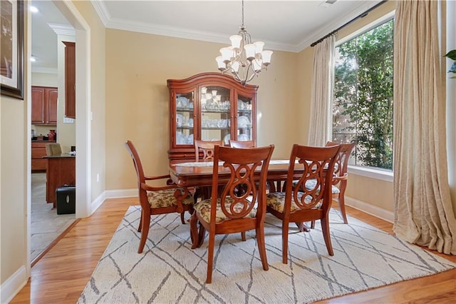 dining space with ornamental molding, a healthy amount of sunlight, and light hardwood / wood-style flooring