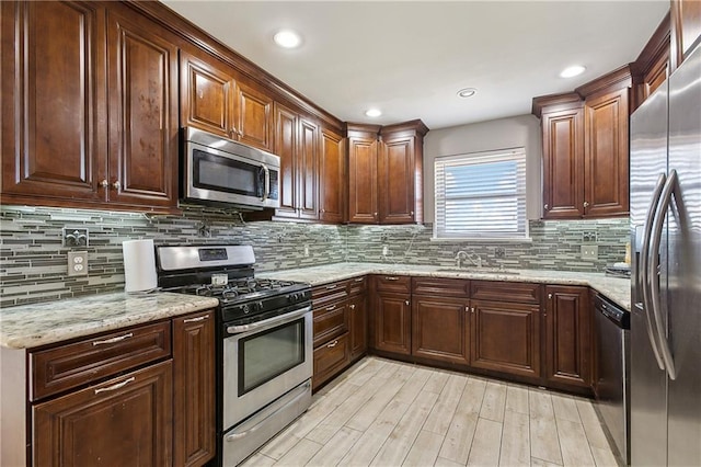 kitchen with stainless steel appliances, light stone countertops, sink, and decorative backsplash