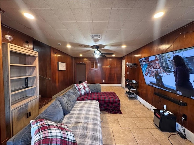 cinema room featuring light tile patterned flooring, ceiling fan, and wood walls