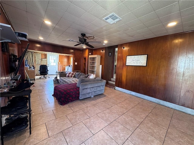 living room featuring tile patterned flooring, ceiling fan, and wood walls