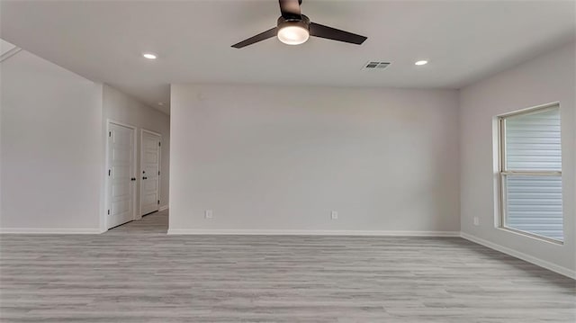 spare room featuring ceiling fan, a wealth of natural light, and light wood-type flooring