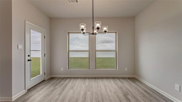 unfurnished dining area with an inviting chandelier and light hardwood / wood-style flooring