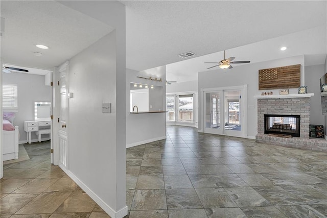 unfurnished living room featuring ceiling fan and a fireplace