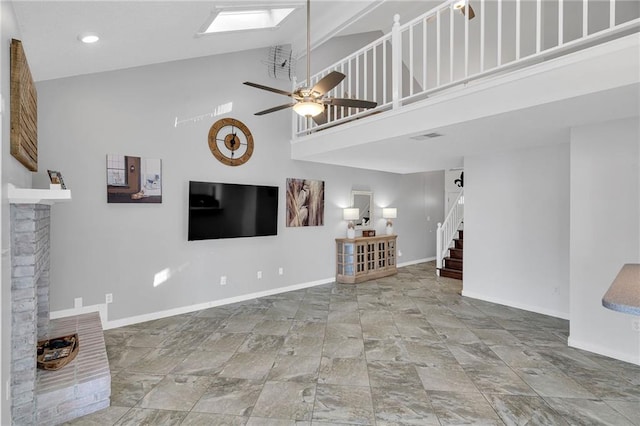 unfurnished living room with a towering ceiling, a fireplace, and ceiling fan