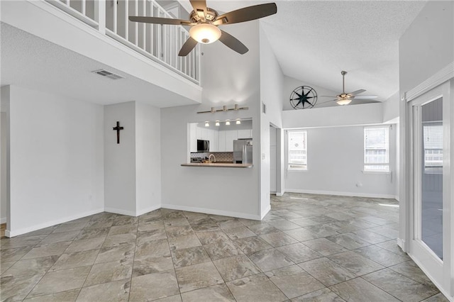 unfurnished living room featuring ceiling fan, high vaulted ceiling, and a textured ceiling