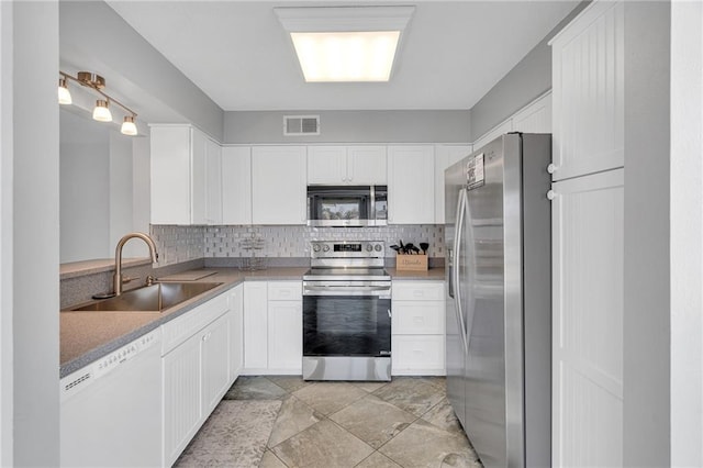 kitchen with white cabinetry, stainless steel appliances, sink, and decorative backsplash