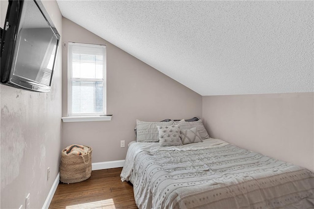 bedroom featuring hardwood / wood-style flooring, vaulted ceiling, and a textured ceiling