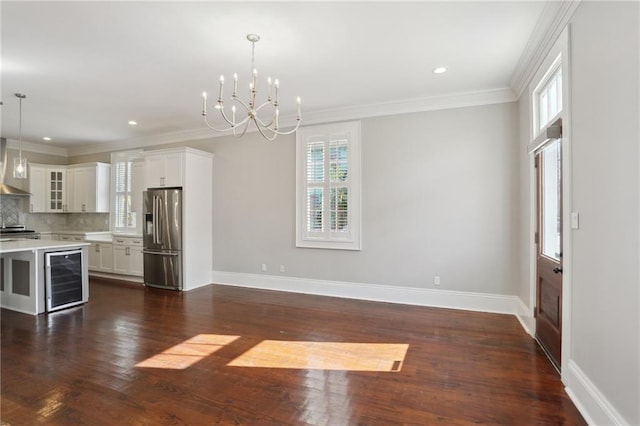 kitchen featuring pendant lighting, high end fridge, an inviting chandelier, tasteful backsplash, and white cabinets