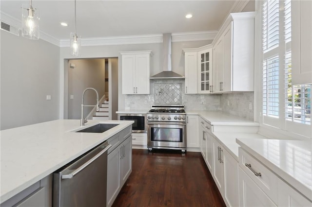 kitchen featuring appliances with stainless steel finishes, white cabinetry, sink, backsplash, and wall chimney range hood