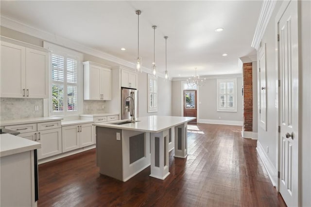 kitchen with an island with sink, hanging light fixtures, and white cabinets