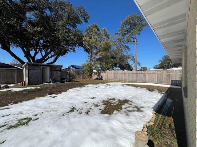 yard layered in snow featuring a storage shed