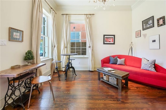 sitting room with dark wood-type flooring, ornamental molding, and an inviting chandelier