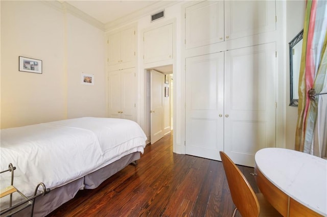 bedroom featuring dark wood-type flooring, ornamental molding, and a closet