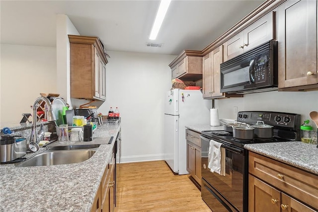 kitchen with sink, black appliances, and light wood-type flooring