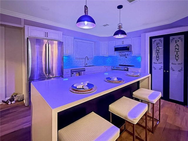 kitchen with a kitchen bar, a center island, appliances with stainless steel finishes, pendant lighting, and white cabinets