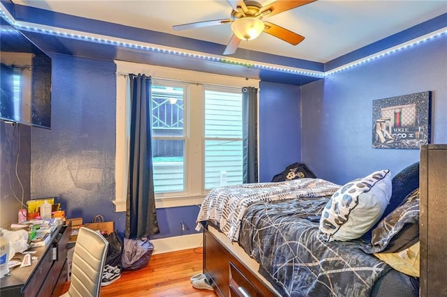 bedroom with multiple windows, hardwood / wood-style floors, and ceiling fan