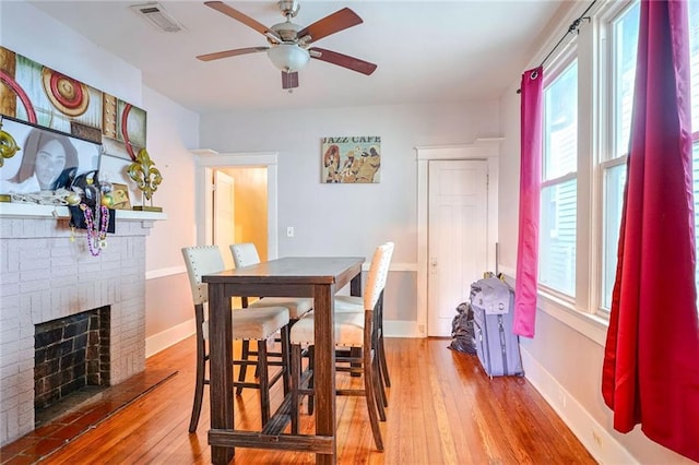 dining space with hardwood / wood-style flooring, a fireplace, and ceiling fan