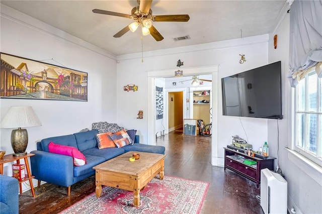 living room with ceiling fan, crown molding, dark wood-type flooring, and a healthy amount of sunlight