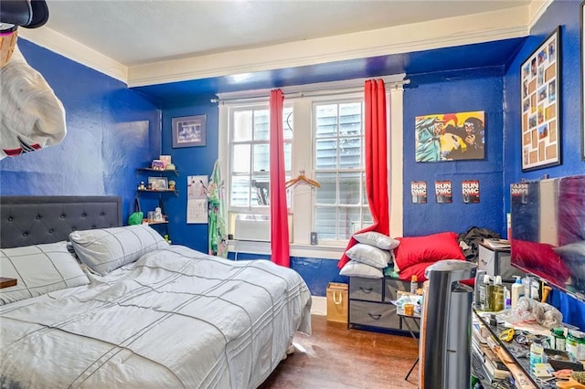 bedroom featuring crown molding, hardwood / wood-style flooring, and ornate columns