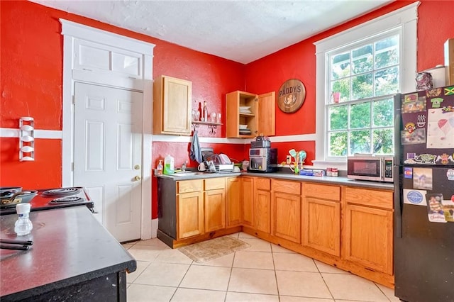 kitchen featuring black fridge and light tile patterned floors