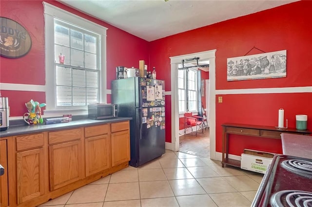 kitchen with light tile patterned flooring and black fridge