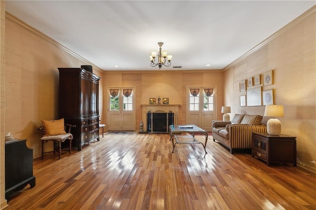 living room with ornamental molding, hardwood / wood-style floors, and a notable chandelier