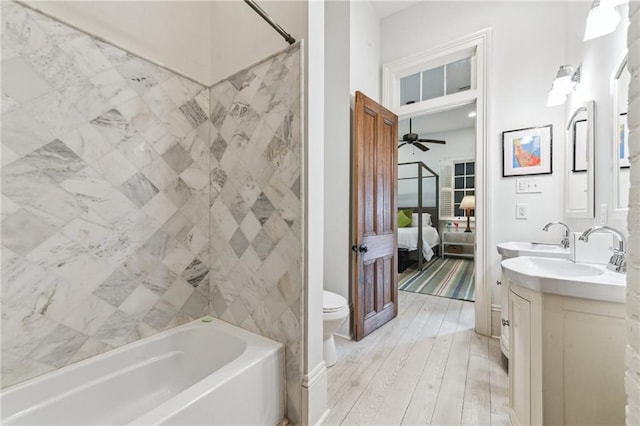 full bathroom featuring hardwood / wood-style flooring, ceiling fan, shower / bath combination, vanity, and toilet