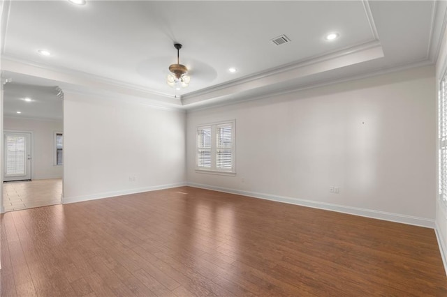 spare room featuring hardwood / wood-style floors, crown molding, and a raised ceiling