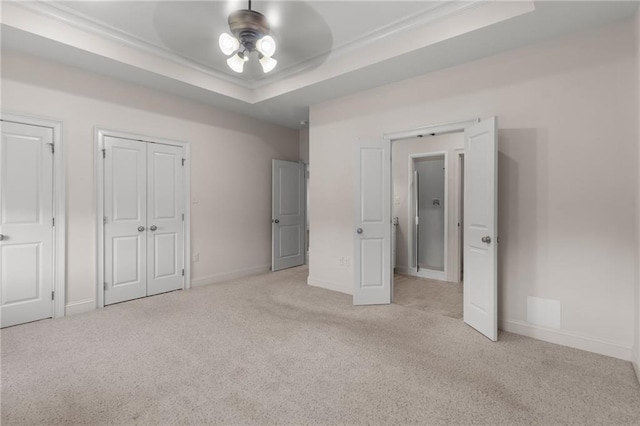 unfurnished bedroom featuring ceiling fan, light colored carpet, and a tray ceiling