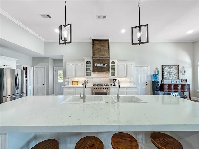 kitchen featuring pendant lighting, white cabinetry, appliances with stainless steel finishes, and a large island with sink