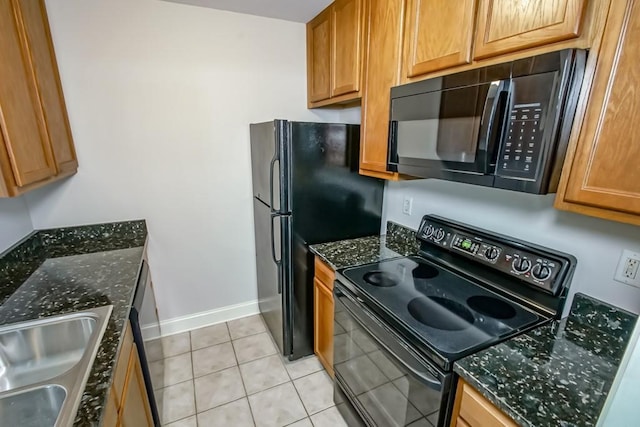 kitchen with dark stone counters, sink, light tile patterned floors, and black appliances