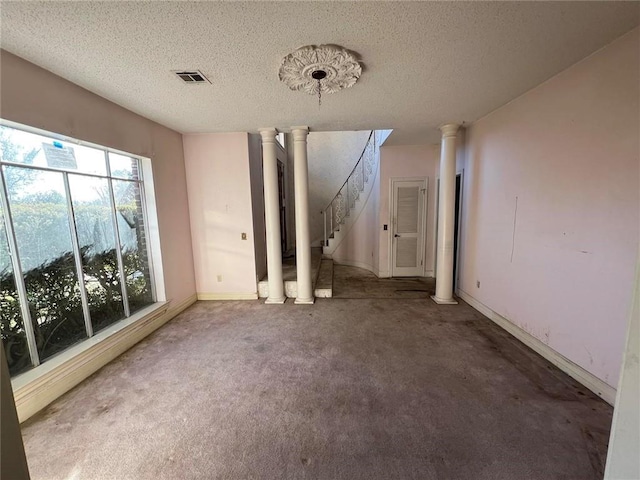 interior space with ornate columns, carpet flooring, and a textured ceiling