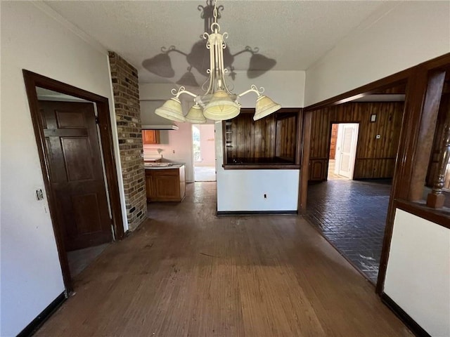 kitchen with wooden walls, dark hardwood / wood-style flooring, and hanging light fixtures