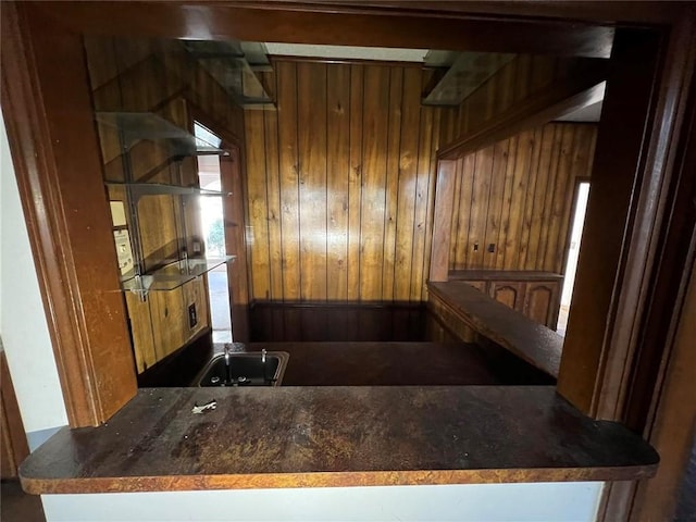 kitchen featuring wooden walls, kitchen peninsula, and sink