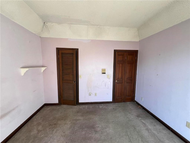 empty room featuring vaulted ceiling, a textured ceiling, and carpet flooring