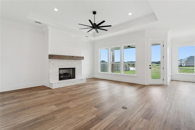 unfurnished living room with hardwood / wood-style flooring, a fireplace, a raised ceiling, and ceiling fan