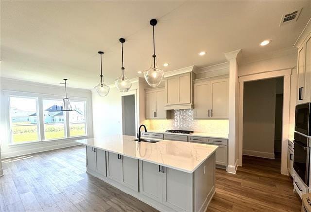 kitchen featuring pendant lighting, gray cabinets, a kitchen island with sink, and black appliances