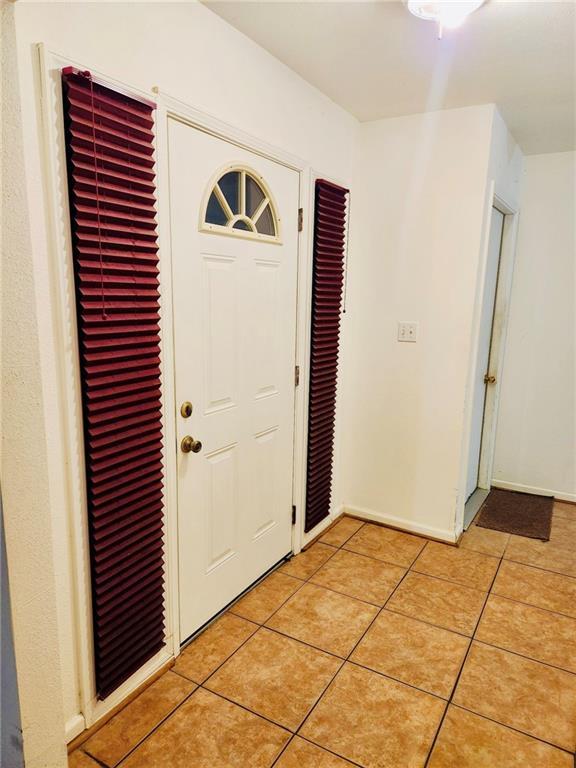 foyer entrance featuring light tile patterned floors and baseboards