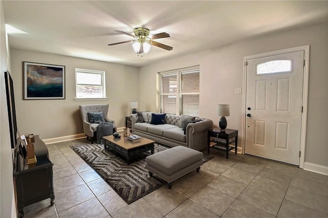 living area with light tile patterned floors, a ceiling fan, and baseboards