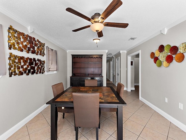 tiled dining area featuring crown molding, ceiling fan, and a textured ceiling