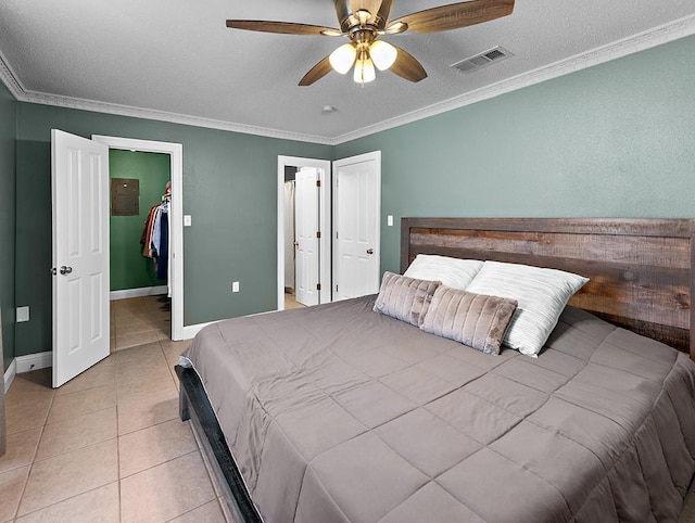 bedroom with ornamental molding, a walk in closet, light tile patterned flooring, and ceiling fan