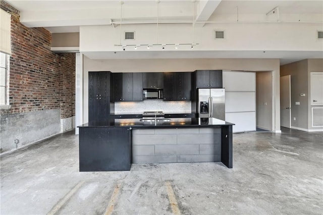 kitchen with visible vents, dark countertops, black microwave, a sink, and stainless steel refrigerator with ice dispenser