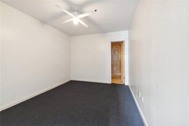 unfurnished room with baseboards, dark carpet, and a ceiling fan